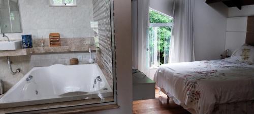 ein Badezimmer mit einer Badewanne neben einem Bett in der Unterkunft Casa de Campo - Vista da montanha in Itaipava