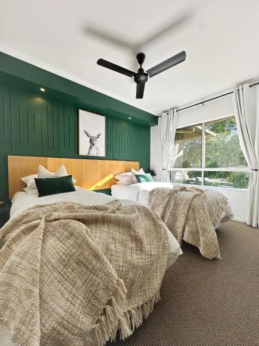 two beds in a bedroom with green walls at Luxury 2 Bedroom apartment, Treetop views, Resort with 4 swimming pools in Cairns North