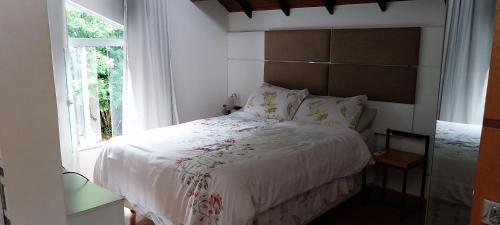 a bedroom with a white bed with a window at Casa de Campo - Vista da montanha in Itaipava