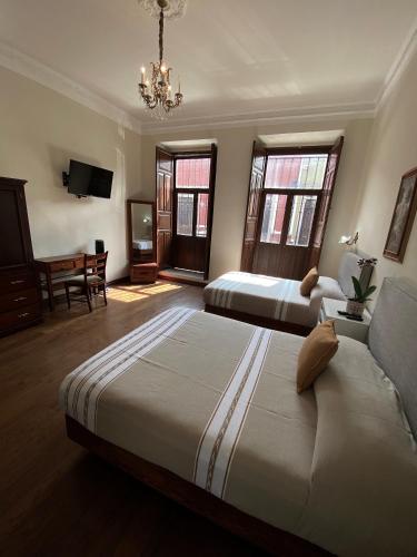 Habitación de hotel con 2 camas y lámpara de araña. en Hotel Cantera Real, Morelia, en Morelia