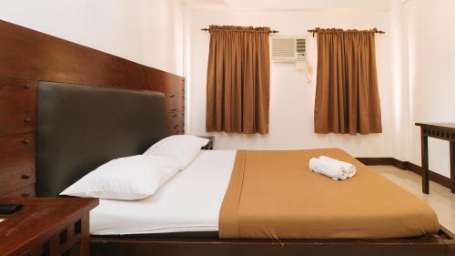 a bedroom with a large bed with white pillows at WestCourt Inn Ilocos Sur in Bantaoay