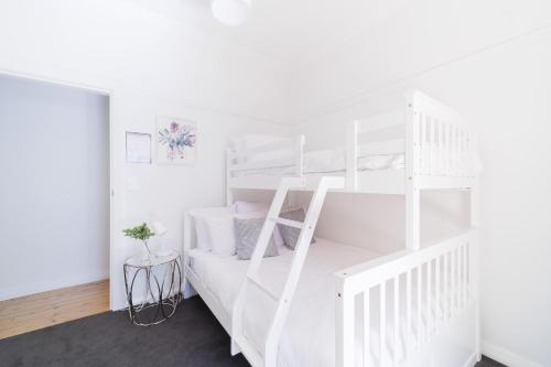 ein weißes Etagenbett in einem weißen Schlafzimmer in der Unterkunft La Villette sleeps 9 fireplace BBQ Pet Friendly in Katoomba