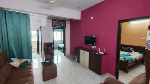 a living room with a couch and a pink wall at sannidhi homestay 1bhk and 2bhk apartment in Tirupati