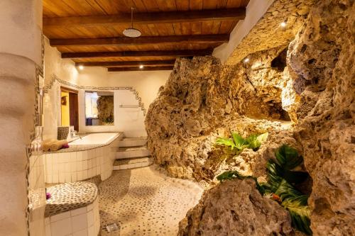 e bagno con parete di roccia e vasca. di Rockwater Resort all’Isola di Tanna