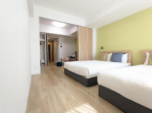 a hotel room with two beds and a hallway at ESLEAD HOTEL Namba South Ⅲ in Osaka