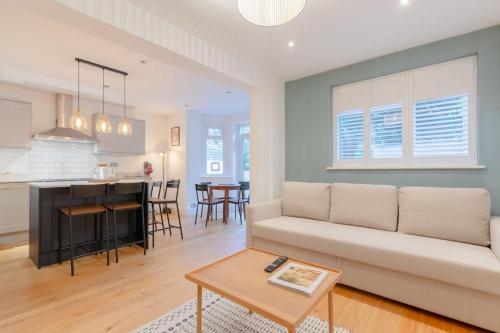 a living room and kitchen with a couch and a table at Newly Refurbished 2BD Flat - Wimbledon Village! in London