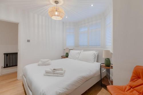 biała sypialnia z białym łóżkiem i żyrandolem w obiekcie Newly Refurbished 2BD Flat - Wimbledon Village! w Londynie