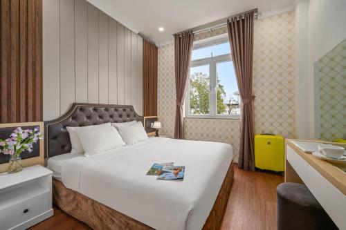 a bedroom with a large white bed and a window at Be U Hotel City View in Da Lat