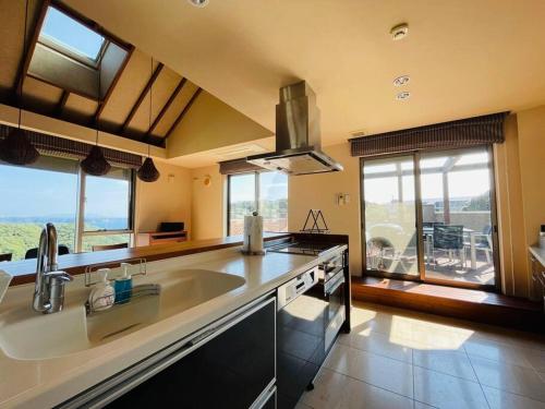 a large kitchen with a large sink and windows at Ocean View Luxury Beach House - Enjoy Spring Cherry Blossoms, Beaches and BBQ at a Luxury Home in Shimoda