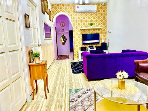 een woonkamer met een paarse bank en een tv bij Danisha Homestay in Kampong Baru
