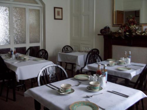 a dining room with two tables with white tableclothsurrencyangering at Denecrest Guest House in Windermere
