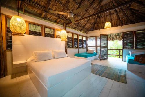 um quarto com uma cama branca e algumas janelas em Hotel Playa Scondida em Barú