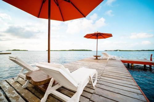 a dock with chairs and umbrellas on the water at Hotel Playa Scondida Barú in Baru