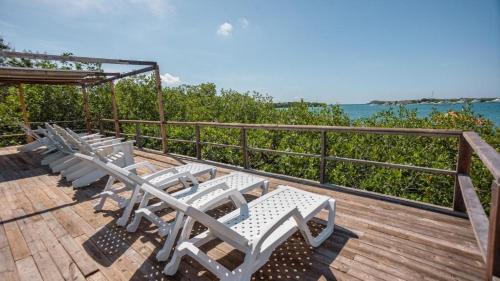 a row of white chairs on a deck with the ocean at Hotel Playa Scondida Barú in Baru