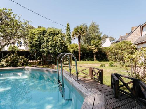 une piscine avec une terrasse en bois à côté d'une maison dans l'établissement Villa familiale 7 pièces à Carnac - 10 pers, piscine chauffée, jardin, proche plage et commerces - FR-1-477-242, à Carnac