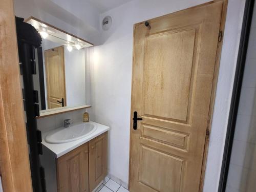 La salle de bains est pourvue d'un lavabo et d'une porte en bois. dans l'établissement Appartement cosy avec terrasse ensoleillée, au pied des pistes de Montgenèvre, tout équipé - FR-1-266-219, à Montgenèvre