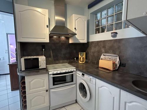 une cuisine avec des armoires blanches et une laveuse et une sécheuse dans l'établissement Maison près du port, avec cour, terrasse équipée, à 400m de la plage - FR-1-224B-209, à Noirmoutier-en-l'lle