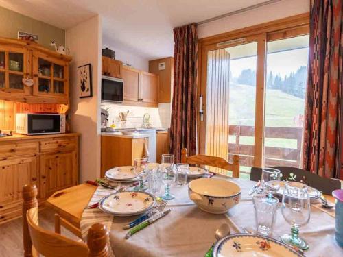 une cuisine avec une table avec des assiettes et des verres dessus dans l'établissement Appartement chaleureux 5 pers. à Valmorel - Avec balcon et acceptant chiens - FR-1-291-1004, à Valmorel