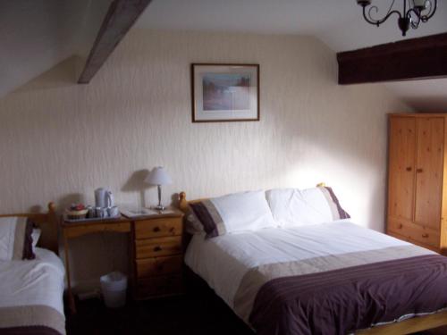 1 dormitorio con 1 cama y mesita de noche con escritorio en Denecrest Guest House, en Windermere