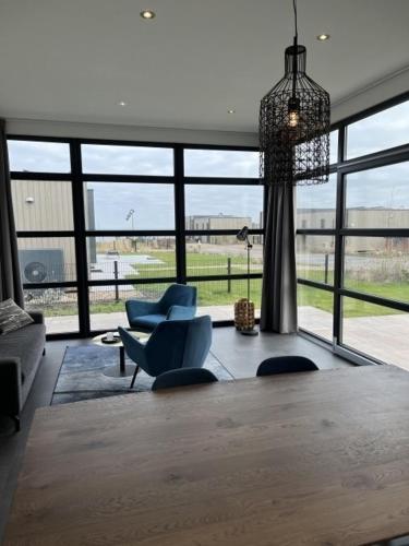 a living room with two blue chairs and a chandelier at Enkhuizer Strand Chalet Meeresbrise Dritte Reihe mit Zaun Haus Nr 251 in Enkhuizen