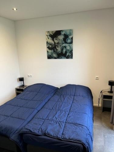 a bed in a room with a blue blanket on it at Enkhuizer Strand Chalet Meeresbrise Dritte Reihe mit Zaun Haus Nr 251 in Enkhuizen