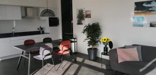 ein Wohnzimmer mit einem Tisch, Stühlen und einem Sofa in der Unterkunft Enkhuizer Strand Chalet Sonnenblume Vierte Reihe mit Zaun Haus Nr 234 in Enkhuizen