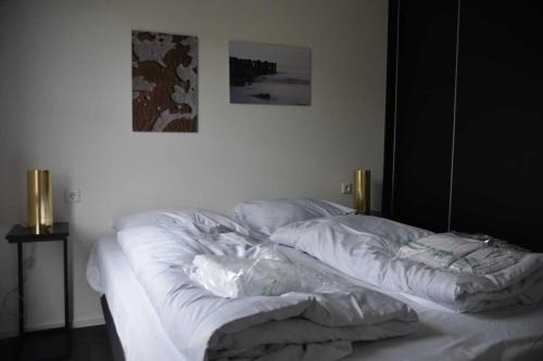 ein unmaskiertes Bett in einem weißen Zimmer mit einem Bild an der Wand in der Unterkunft Enkhuizer Strand Chalet Sonnenblume Vierte Reihe mit Zaun Haus Nr 234 in Enkhuizen