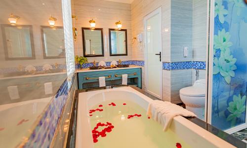 y baño con bañera, lavabo y aseo. en Vườn Vua Resort & Spa -by Bay Luxury, en Ðồng Phú