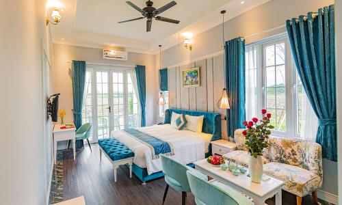 1 dormitorio con 1 cama, mesa y sillas en Vườn Vua Resort & Spa -by Bay Luxury, en Ðồng Phú