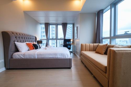 a bedroom with a bed and a couch at Spacious 2BR Apartment in BGC with Workspace & Washer in Manila