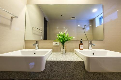 un bagno con due lavandini e un grande specchio di Spacious 2BR Apartment in BGC with Workspace & Washer a Manila