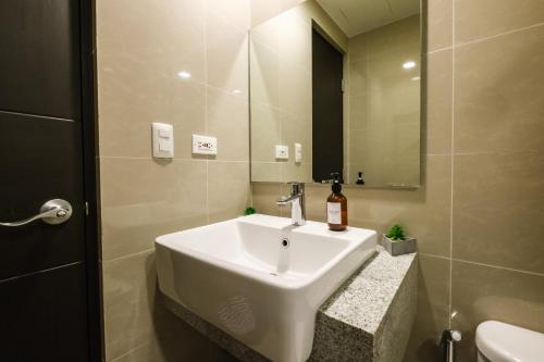 a bathroom with a white sink and a mirror at Spacious 2BR Apartment in BGC with Workspace & Washer in Manila