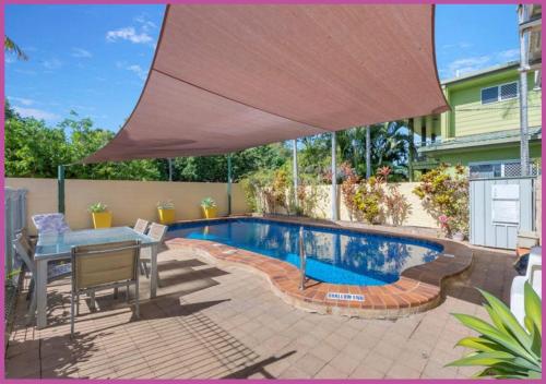 a swimming pool with a table and a large umbrella at Walk to Strand Sleeps*4 2 Bedroom 1.5 Bath Central Location in Townsville