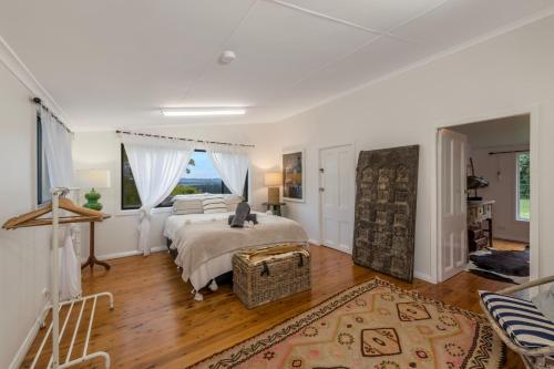 a bedroom with a bed and a large window at Clover Hill Cottage, between Gerroa and Berry in Broughton Vale