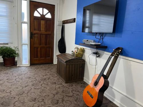 uma guitarra numa sala com uma parede azul em Casa em Punta Arenas