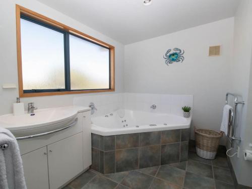 y baño con bañera y lavamanos. en Beachfront Bliss On Wanaka Terrace Support Local, en New Plymouth