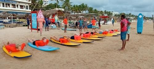a group of children laying on surfboards on a beach at Hotel Universal Beach in Hikkaduwa