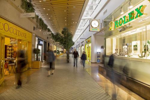 people walking through a shopping mall with a clock on the ceiling at Royal Garden by Isrotel Collection in Eilat