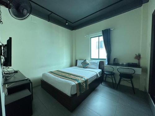 Schlafzimmer mit einem Bett, einem Schreibtisch und einem Fenster in der Unterkunft Saigon Chill Hostel in Ho-Chi-Minh-Stadt
