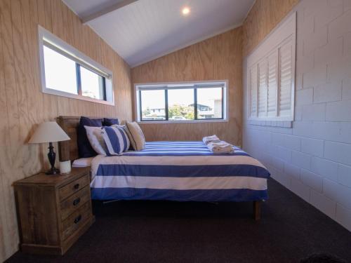 um quarto com uma cama e duas janelas em The Boat House On Dixon em Oakura