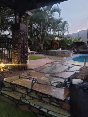 a backyard with a stone patio and a swimming pool at Robbins Estate in Wailuku