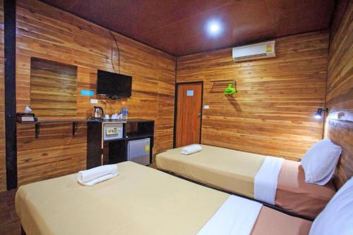 two beds in a room with wooden walls at The Cobble Beach Hotel- Phi Phi Island in Phi Phi Don