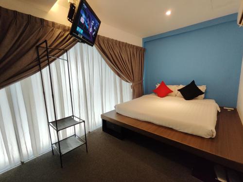 een slaapkamer met een bed en een televisie aan de muur bij Ryokan Chic Hotel in Petaling Jaya