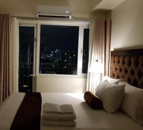 1 dormitorio con ventana y vistas a la ciudad en Studio unit at The Breeze Residence en Manila