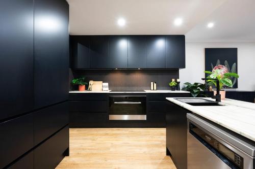 a kitchen with black cabinets and a counter top at Cicada Close Hideaway in Buderim