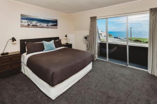 a bedroom with a large bed and a large window at Blue Haven On Belt Waterfront in New Plymouth