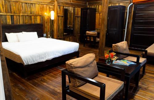 1 dormitorio con 1 cama, mesa y sillas en Thai Hai Village - Bản làng Thái Hải, 