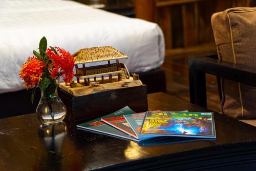 una mesa con un jarrón de flores y un libro en Thai Hai Village - Bản làng Thái Hải, 