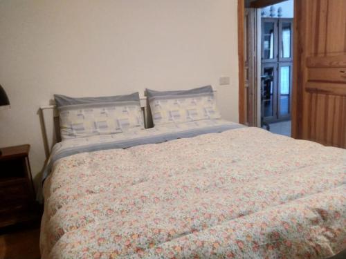 1 dormitorio con 1 cama grande con colcha de flores en Breakfast in garden mountain view, en Calalzo