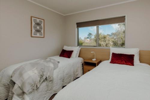 Duas camas num quarto com uma janela em Salt Life Oakura Beach em Oakura